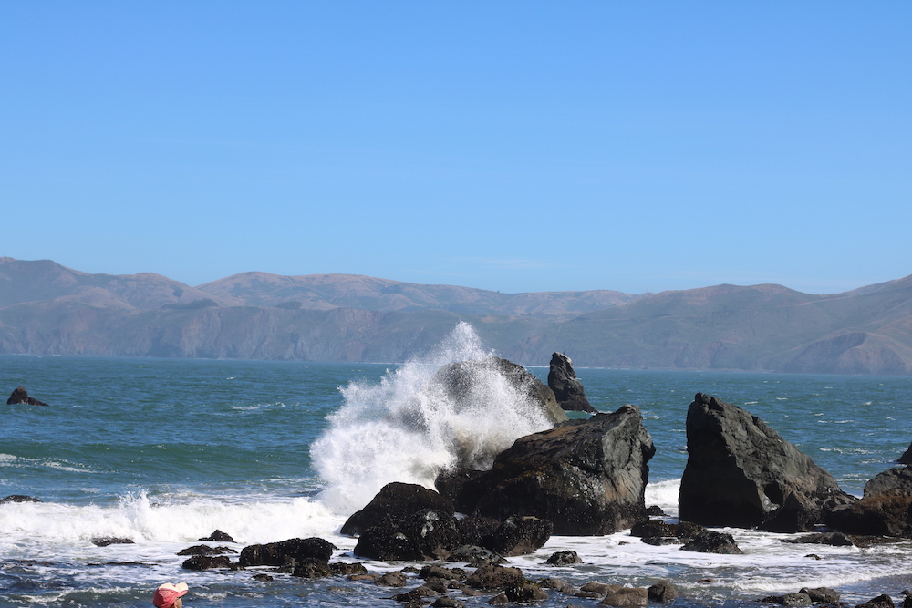 a wave in the Pacific Ocean at Lands End crashing into a rock at Mile Rock Beach in San Francisco, California