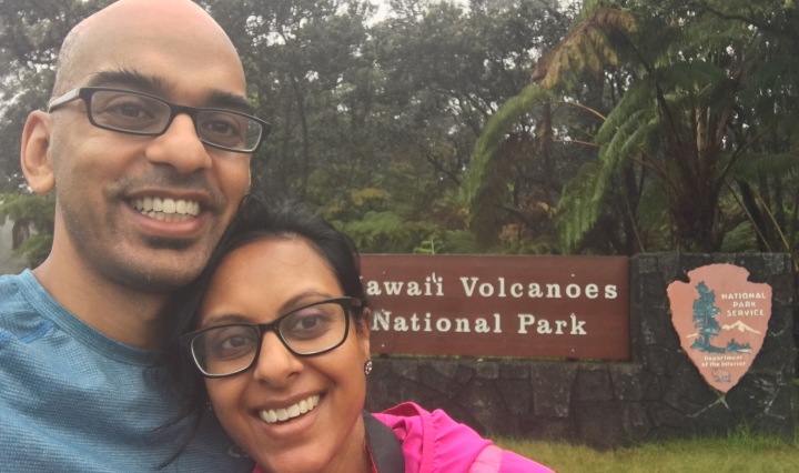 husband and wife standing in front of entrance to Hawaii Volcano National Park